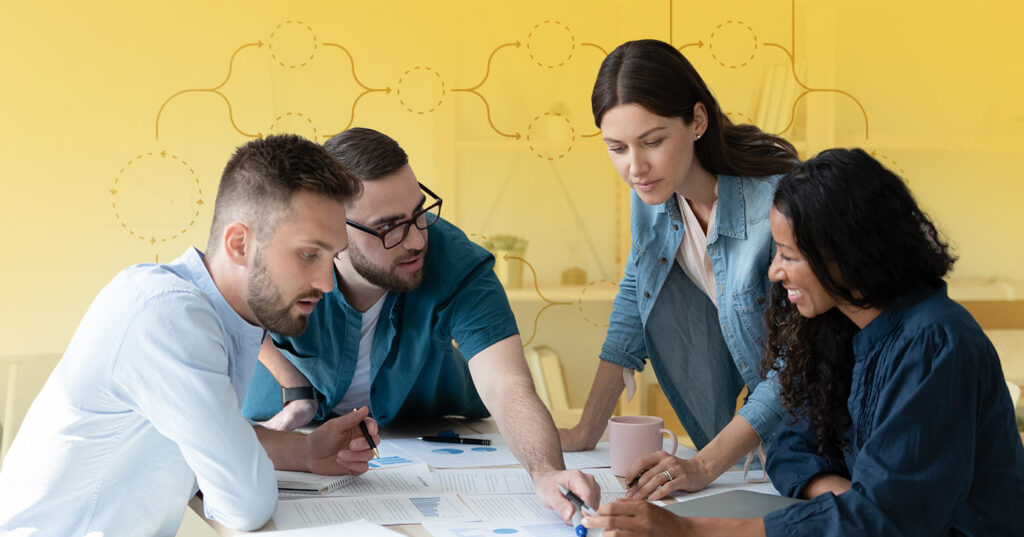 four people looking over business documents on a table to achieve an agile email marketing process