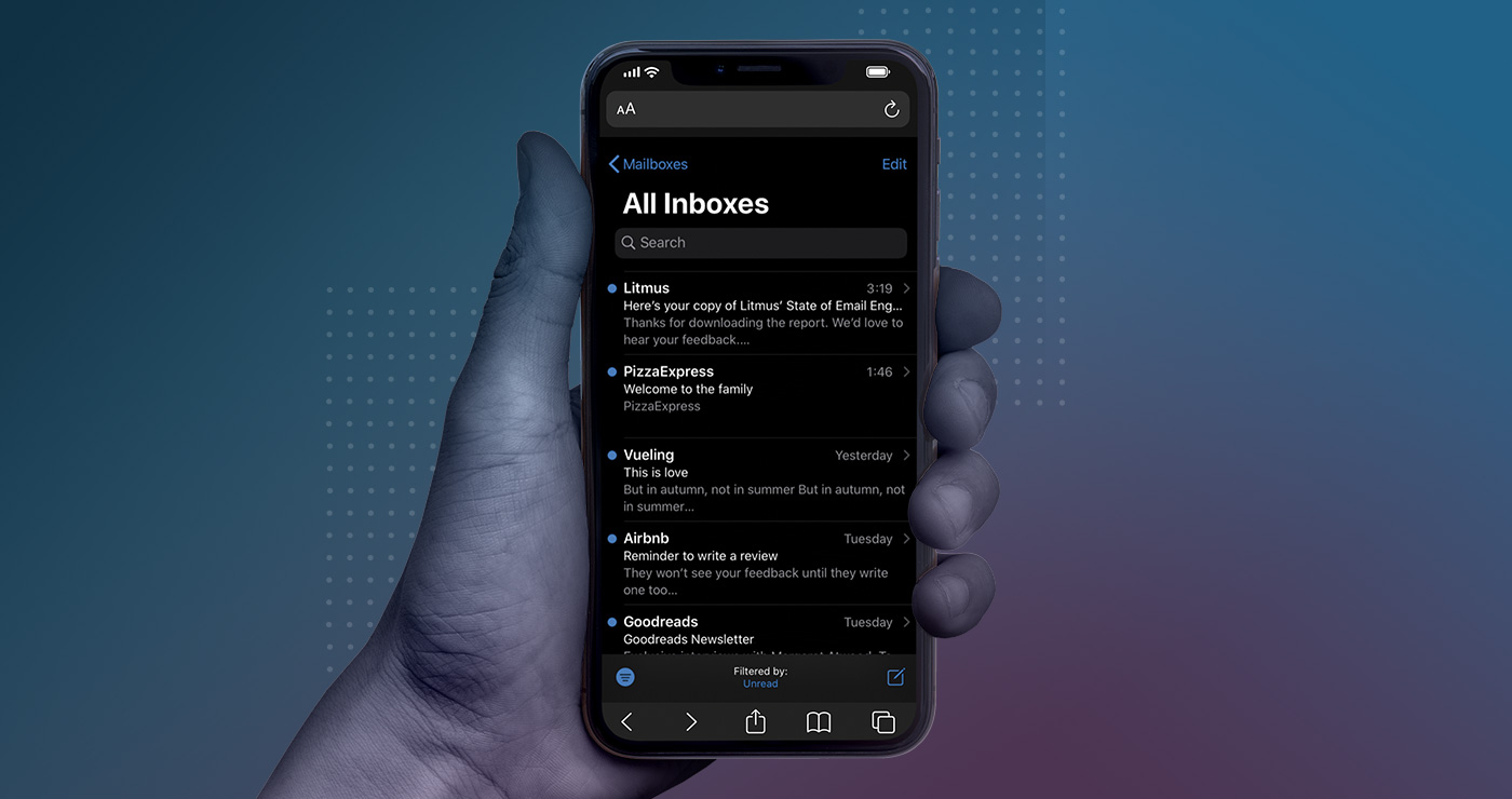 hand holding up an apple iphone with apple mail in dark mode